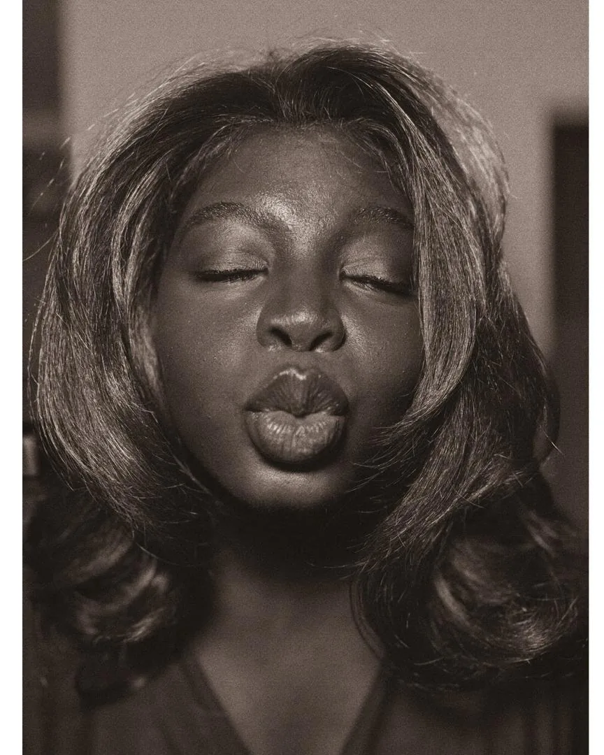 Sepia portrait of Jemima, eyes closed, blowing a kiss at the camera
